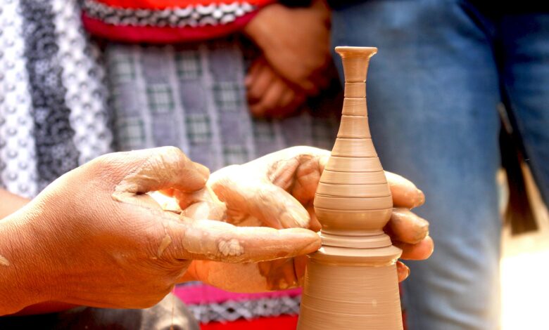 Close-up of artisan shaping a delicate clay vase with hands, showcasing skill and tradition.