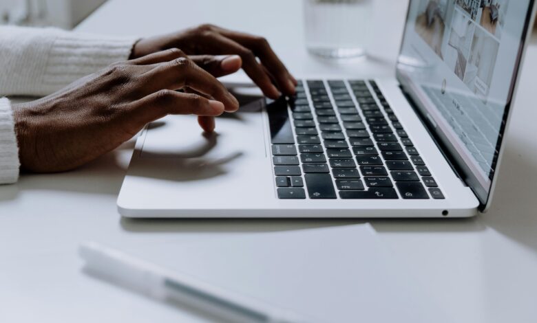 Hands typing on a sleek laptop keyboard, illustrating modern technology in use.