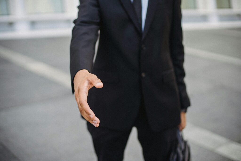 pexels-photo-4965006-4965006 Close-up of a businessman in a suit reaching out for a handshake, symbolizing connection.